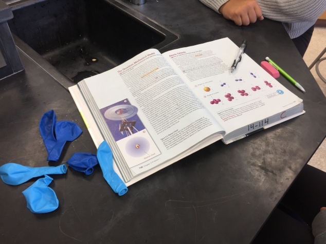 Students use their textbook to help them figure out how to build their orbitals using balloons. These students chose to use shades of blue for one of their orbitals. 